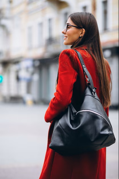 Visuel femme dans une rue habillée d'un manteau rouge et d'une besace en cuir noir