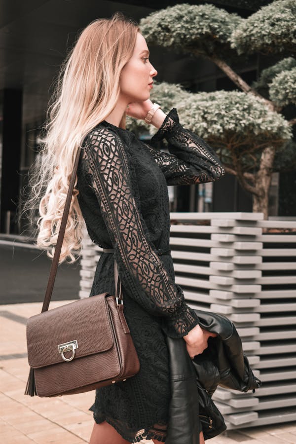 Visuel jeune femme dans jardin public avec sac a main cuir à l'épaule et manteau à la main