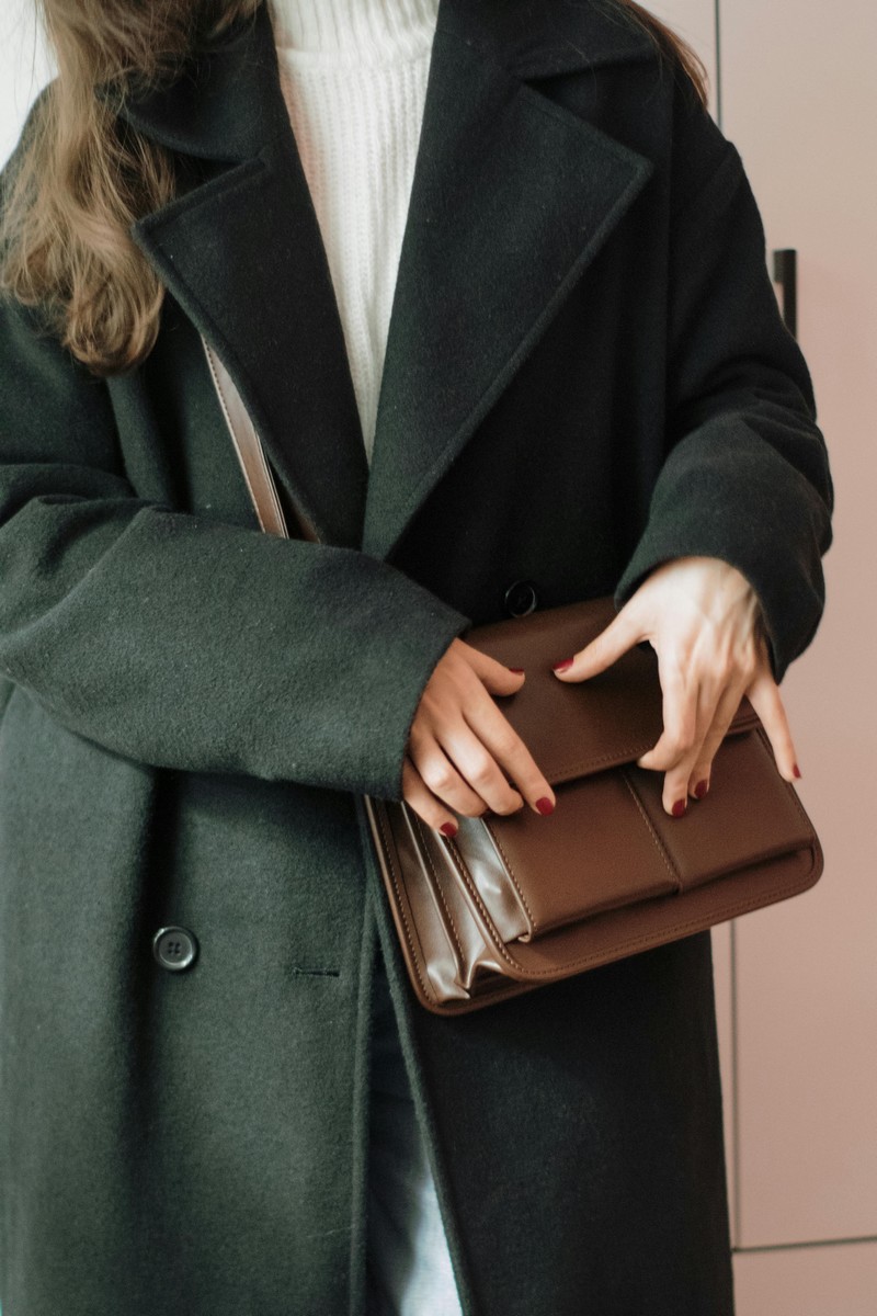 Visuel femme habillée d'un manteau et d'un sac cuir intemporel